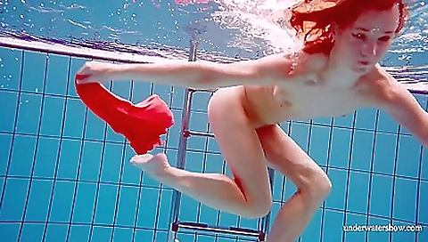 Sexy redhead with a red dress swallows her pussy in the pool